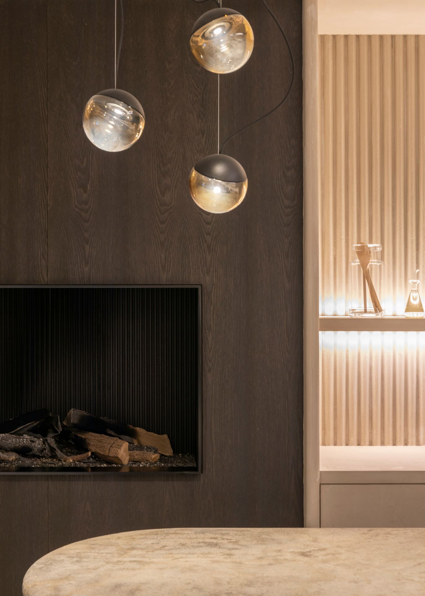 Modern interieur met sfeervolle haard, geïntegreerde verlichting en houten wandafwerking.